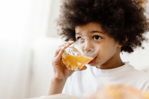 a child smiling and drinking from a cup